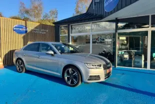 Audi A4 1.4 TFSI argent fleuret métallisé vue 3/4 avant sur parking bleu devant concession Distinxion