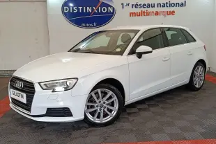 Audi A3 blanc vue 3/4 avant droit, avec jantes alliage et phares LED, en intérieur showroom.
