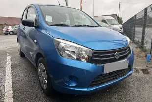 Vue 3/4 avant gauche d'une Suzuki Celerio 2015 bleu avec calandre noire et phares larges sous la pluie.