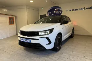 Vue 3/4 avant droite d’un Opel Grandland blanc avec toit noir et jantes noires, en intérieur showroom avec plaque "OCCASION".