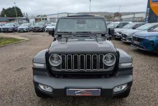 Vue de face du Jeep Wrangler noir avec calandre à sept fentes et phares ronds LED, sur parking extérieur.