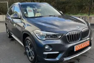 BMW X1 sDrive18d Lounge gris foncé vue 3/4 avant droit avec calandre distinctive et plaque "OCCASION" orange.
