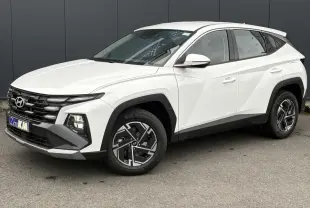 Hyundai Tucson blanc Atlas en 3/4 avant droit, avec jantes alliage et calandre noire distinctive.