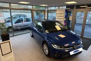 Volkswagen Polo Style TSI 116Ch DSG bleu récif vue 3/4 avant dans un showroom lumineux avec sol carrelé.
