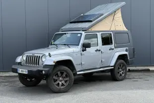 Jeep Wrangler Billet Silver vue 3/4 avant droit avec toit relevable beige et panneau solaire intégré.