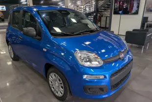 Fiat Panda 1.0 Hybrid City bleu Italia vue 3/4 avant droit en intérieur, avec jantes acier et rétroviseurs noirs.