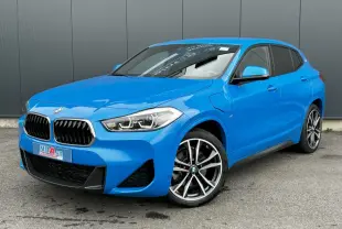 BMW X2 xDrive 25e bleu Misano en 3/4 avant droit, avec jantes alliage bicolores et calandre M Sport visible.