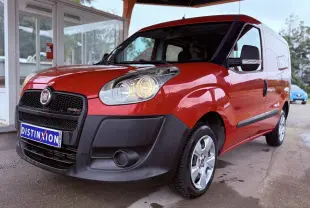 Vue 3/4 avant droit d’un FIAT Doblo Cargo rouge avec pare-chocs noirs et jantes argentées sous abri.
