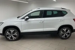 Profil droit du SUV SEAT Ateca blanc Nevada avec jantes alliage 18 pouces et toit équipé de barres de toit.