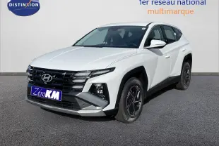 Hyundai Tucson blanc Atlas en 3/4 avant droit, avec calandre noire et jantes bi-ton distinctives.