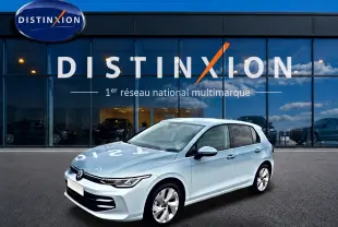 Volkswagen Golf 2026 bleu glacier vue 3/4 avant droit devant vitrine Distinxion avec reflets sur carrosserie.