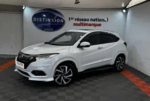 Honda HR-V blanc vue 3/4 avant droit, avec jantes noires et toit noir dans un showroom intérieur.