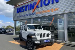 Jeep Wrangler blanc vu de face à 3/4 gauche, avec calandre à sept fentes et jantes noires distinctives.