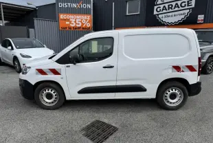 Profil côté gauche d'un utilitaire Citroën Berlingo blanc avec bandes réfléchissantes rouges et protections noires.