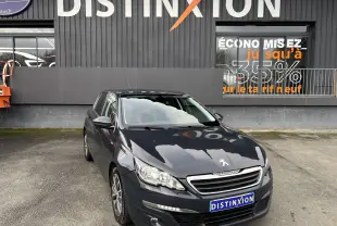 Peugeot 308 gris vue 3/4 avant droit, avec phares LED et jantes alliage biton visibles devant un bâtiment Distinxion.