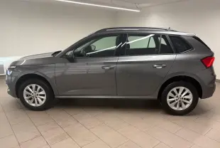 Vue de profil côté gauche d'un Skoda Kamiq 2023 gris graphite métallisé avec jantes alliage en intérieur neutre.