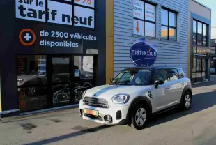 MINI Countryman gris perle métal avec toit noir, vue 3/4 avant droit devant un bâtiment commercial.