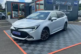 Toyota Corolla Touring Sport blanche vue en 3/4 avant droit, avec jantes alliage et calandre noire distinctive.