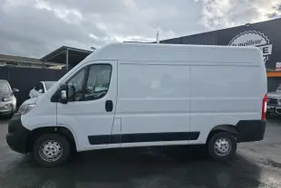 Profil côté gauche d'un fourgon Opel Movano blanc avec panneaux latéraux bois et porte coulissante tôlée.