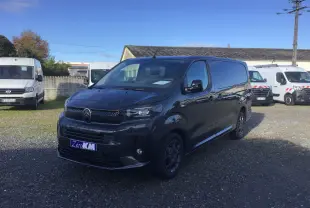Vue 3/4 avant d'un Citroën Jumpy cabine approfondie gris titane, avec calandre noire et jantes spécifiques, stationné en extérieur.