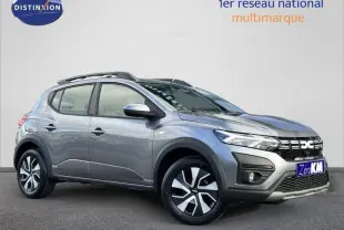 Vue 3/4 avant droite d'une Dacia Sandero Stepway grise avec jantes alliage et barres de toit noires