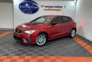 SEAT Ibiza 1.0 TSI 110 FR rouge vue 3/4 avant droit dans un showroom avec sol noir et orange.