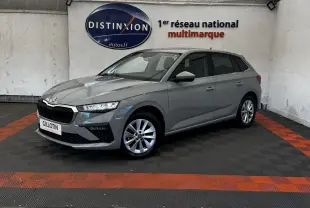 Vue 3/4 avant droite d'une Skoda Scala gris clair stationnée en intérieur avec jantes alliage et calandre noire distinctive.
