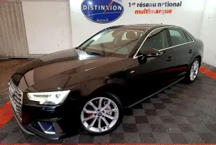 Audi A4 noire en 3/4 avant droit, avec jantes argentées et phares LED allumés en intérieur showroom.