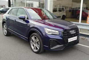 Audi Q2 bleu Navarre en 3/4 avant droit, avec calandre noire et jantes alliage bicolores visibles.