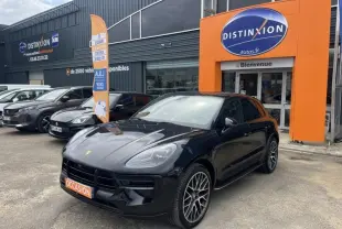 Vue 3/4 avant droite d'un Porsche Macan noir brillant avec jantes sport devant un concessionnaire Distinxion.