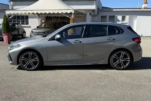 BMW Série 1 118i M Sport gris métallisé vue de profil côté gauche, avec jantes alliage et rétroviseurs alu.