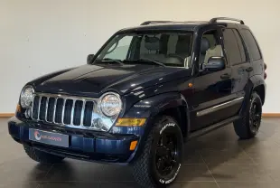 Jeep Cherokee bleu 2005 en 3/4 avant droit, avec calandre chromée et pneus tout-terrain marqués Gripmax.