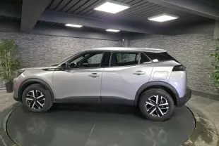 Vue de profil côté gauche d'un Peugeot 2008 gris métallisé avec jantes noires et toit noir contrasté.