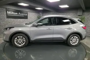 Profil côté gauche du Ford Kuga gris métallisé 2021 dans un showroom avec jantes alliage 17 pouces.