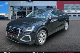 Audi Q2 noir vue 3/4 avant droit, avec jantes alu 5 branches et calandre chromée, stationné devant un garage.
