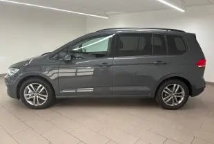 Profil côté gauche d'un Volkswagen Touran 2025 gris dauphin avec jantes alliage 17 pouces en intérieur lumineux.