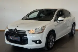 Citroën DS4 blanc vue 3/4 avant droit, avec calandre noire distinctive et phares allumés dans un intérieur neutre.