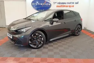 Vue 3/4 avant droite d'une CUPRA BORN gris foncé avec jantes noires et détails sportifs visibles en intérieur showroom.