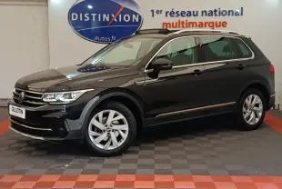Volkswagen Tiguan noir 2021 en vue profil côté gauche, avec jantes alliage et barres de toit chromées visibles.