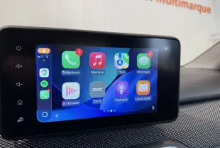 Vue 3/4 avant droite d'une Dacia Sandero gris 2025 avec calandre moderne et jantes noires en showroom.