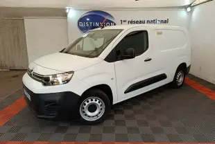 Vue 3/4 avant droite d’un utilitaire Citroën Berlingo XL blanc avec pare-chocs noirs et jantes acier en intérieur showroom.