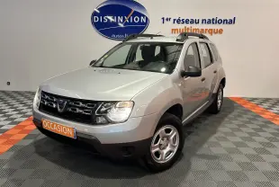 Dacia Duster gris 2017 en 3/4 avant droit avec calandre noire et jantes acier, dans un showroom multimarque.