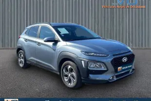 Hyundai Kona Hybrid gris foncé en 3/4 avant droit, avec jantes alliage et vitres surteintées visibles.