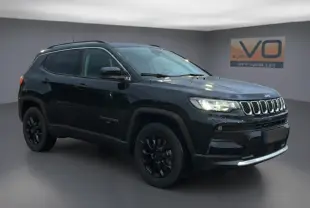 Jeep Compass noir en 3/4 avant droit, avec jantes alliage noires et barres de toit visibles dans un studio.