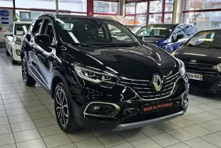 Renault Kadjar noir en 3/4 avant droit dans un showroom, avec jantes bi-ton et calandre chromée visible.