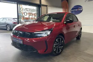Opel Corsa rouge vue 3/4 avant droit en intérieur, calandre noire et jantes alliage diamantées.