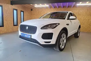 Jaguar E-PACE blanc en 3/4 avant droit, avec calandre distinctive et phares LED dans un garage en bois.