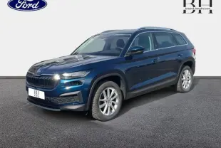 Vue 3/4 avant droite d'un Skoda Kodiaq 2023 bleu lave métallisé avec jantes alu et barres de toit.