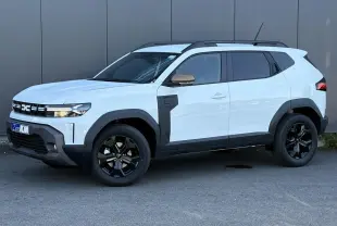Dacia Duster Blanc Glacier en vue 3/4 avant droit, avec jantes noires et détails noirs contrastants sur les ailes.