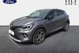 Renault Captur gris Cassiopée en 3/4 avant droit, avec jantes alu et feux LED distinctifs.